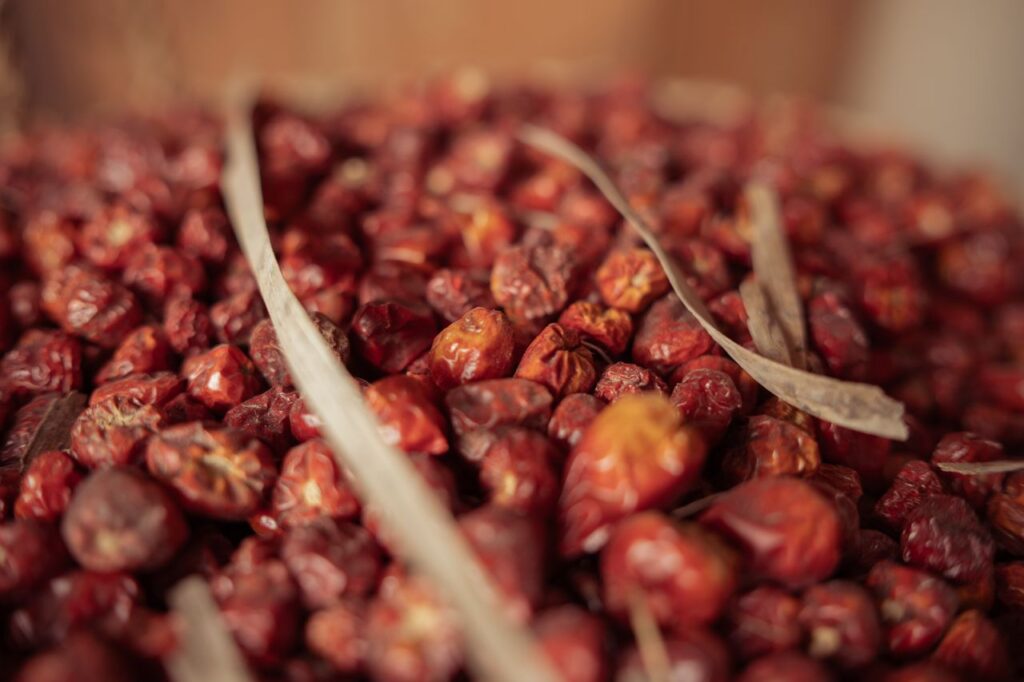 Detailed close-up of a pile of dried red jujube fruits with brown stems, showcasing their textures.